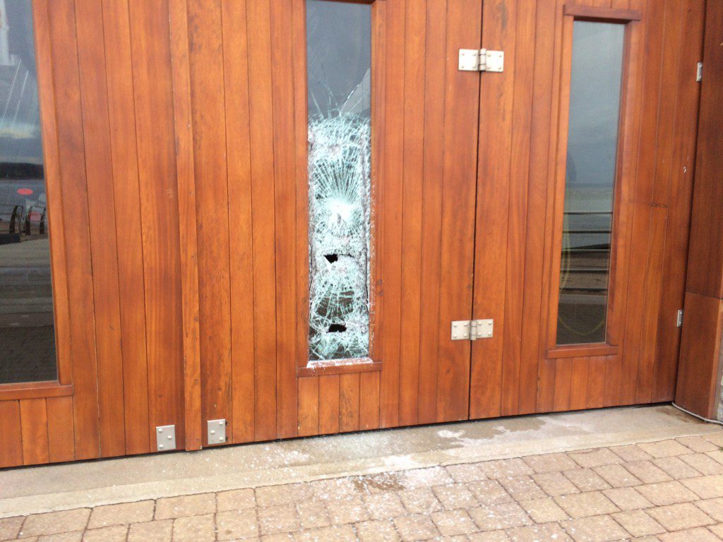 Photo Credit: Exmouth RNLI.  Smashed window on the all-weather lifeboat hall door.