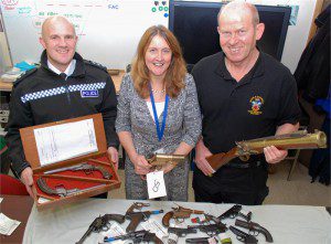 Chief Inspector Daniel Evans with antique duelling pistols, Firearms and Explosives Licensing Manager Michelle Mounsey with WW1 flare pistol, Armourer Mike Barker with replica blunderbuss.